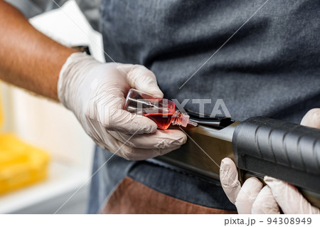 Close up of a man in apron lubricates the mechanism of the weapon with oil 94308949