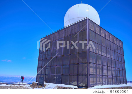 冬の霧ヶ峰(車山)の山頂にある気象レーダーと登山者 94309504