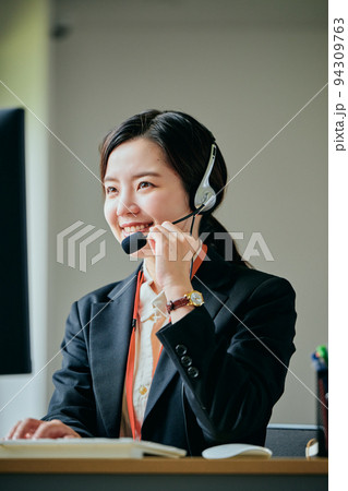オフィスで電話対応する若いオペレーター オフィスで電話対応する若いオペレーター 94309763