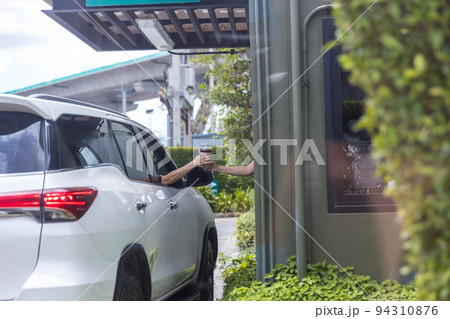 Hand Man in car receiving coffee in drive thru fast food restaurant. Hand Man in car receiving coffee in drive thru fast food restaurant. 94310876