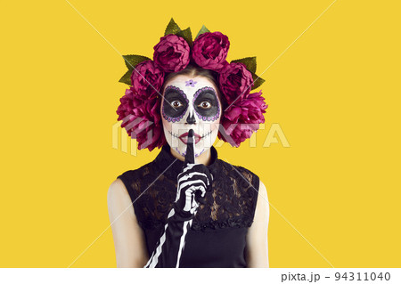 Woman in Day of the Dead or Halloween costume doing shh gesture asking you to keep secret 94311040