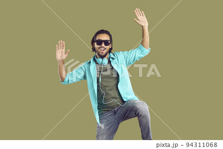Cheerful energetic Indian man with big headphones around his neck having fun on khaki background. Cheerful energetic Indian man with big headphones around his neck having fun on khaki background. 94311068
