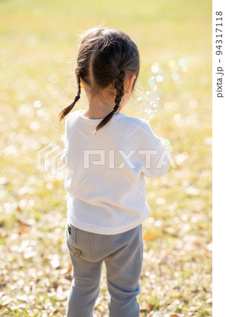 シャボン玉で遊ぶ女の子の後姿 94317118