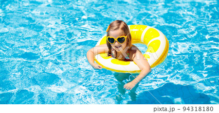 Child in swimming pool on ring toy. Kids swim. 94318180