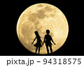 満月を見上げるカップルのシルエット 94318575