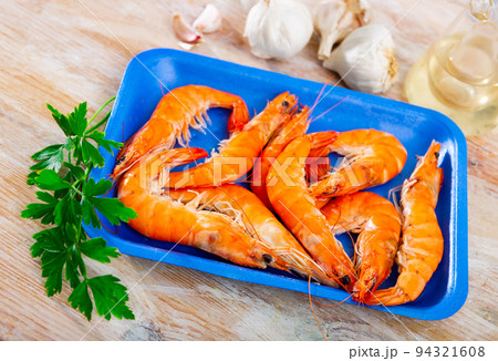Prawns in blue plastic tray with garlic, salt, greens and wine vinegar 94321608