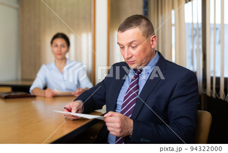 Shocked office employe reading papers with dissatisfied female manager 94322000