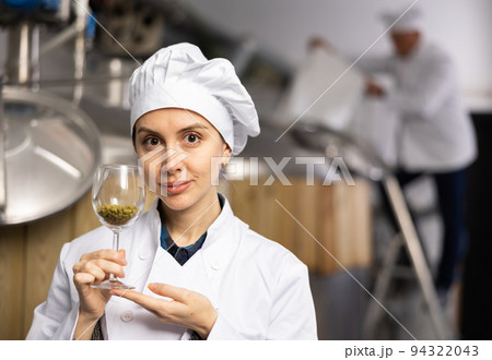 Portrait of woman brewmaster holding glass of hops pellets Portrait of woman brewmaster holding glass of hops pellets 94322043