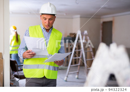 Man builder examining project documentation in apartment 94322324