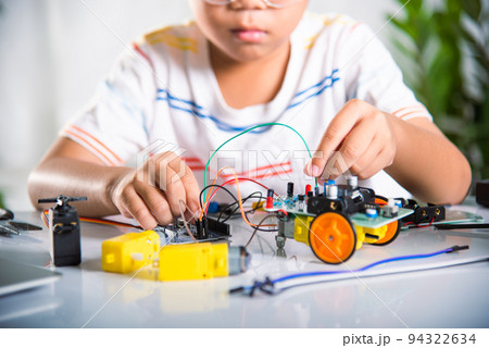 Asian kid boy plugging energy and signal cable to sensor chip with Arduino robot car Asian kid boy plugging energy and signal cable to sensor chip with Arduino robot car 94322634