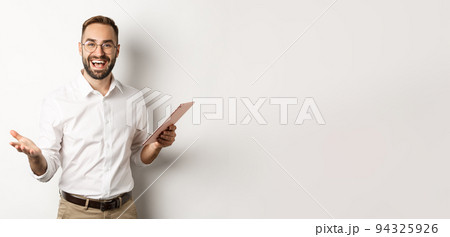 Satisfied businessman praising good work, reading report on digital tablet, standing happy against white background 94325926