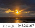 水平線上の雲から輝く夕日 94328107