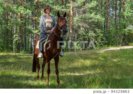 Woman in casual clothes rides a horse in early spring Woman in casual clothes rides a horse in early spring 94329863