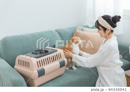 キャリーバッグに猫を入れる女性（通院） 94330041
