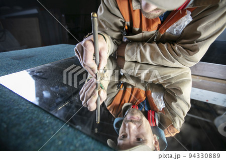 A worker cuts glass with a glass cutter. Furniture manufacturing. 94330889