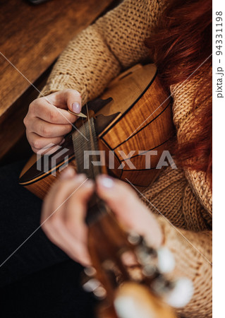 Domra Folk Musical Instrument in womans hand. Female hands with 4 strings Natural Wood Handmade Musical Instrument Domra Close up Domra Folk Musical Instrument in womans hand. Female hands with 4 strings Natural Wood Handmade Musical Instrument Domra Close up 94331198