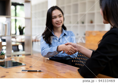 Portrait young asian woman interviewer and adviser shaking hands for a job interview. Business people handshake in modern office. Greeting deal concept 94333469