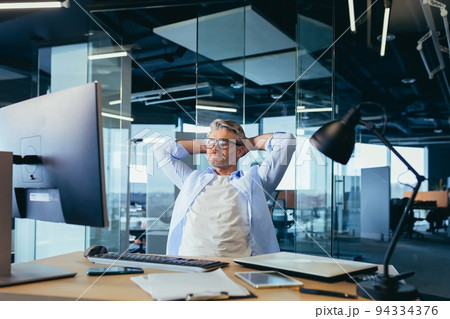 pensive and dreamy experienced businessman owner boss, sitting at work, throwing his hands behind his head, resting pensive and dreamy experienced businessman owner boss, sitting at work, throwing his hands behind his head, resting 94334376