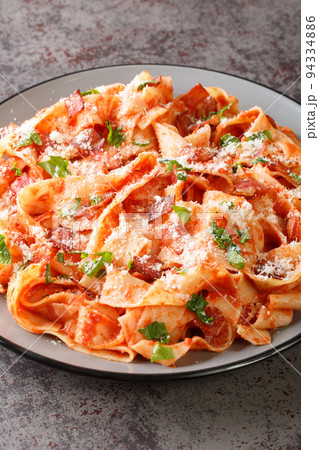 Pappardelle alla Fiesolana is classic Italian comfort food made with pasta, bacon, onion, tomato and parmesan closeup in the plate. Vertical 94334886