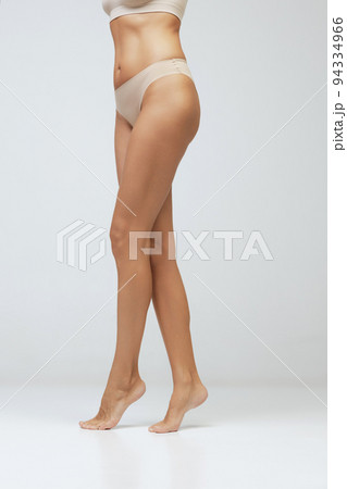 Legs and buttocks. Cropped image of female tanned body of young woman in underwear isolated on gray background. Wellness, weight loss, treatment, health care, fitness Legs and buttocks. Cropped image of female tanned body of young woman in underwear isolated on gray background. Wellness, weight loss, treatment, health care, fitness 94334966