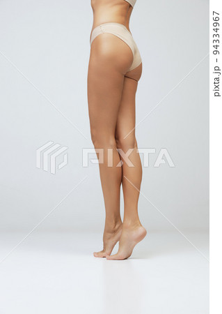 Legs and buttocks. Cropped image of female tanned body of young woman in underwear isolated on gray background. Wellness, weight loss, treatment, health care, fitness Legs and buttocks. Cropped image of female tanned body of young woman in underwear isolated on gray background. Wellness, weight loss, treatment, health care, fitness 94334967