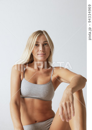 Young pretty slim 35 years old woman in cotton inner wear isolated over gray studio background. Wellness, wellbeing, fitness, diet, natural beauty of female body Young pretty slim 35 years old woman in cotton inner wear isolated over gray studio background. Wellness, wellbeing, fitness, diet, natural beauty of female body 94334969