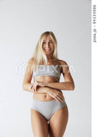 Young pretty slim 35 years old woman in cotton inner wear isolated over gray studio background. Wellness, wellbeing, fitness, diet, natural beauty of female body 94334986