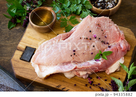 Fresh raw meat. Raw pork meat fillet with olive oil, spices and fresh basil on rustic wooden table. 94335882