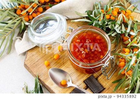 Homemade jam. Glass jar with sea buckthorn jam on rustic background. Preserved berry. Copy space. 94335892