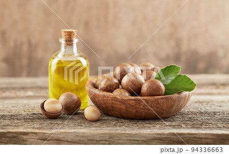 Macadamia nuts with oil on old wooden background Macadamia nuts with oil on old wooden background 94336663