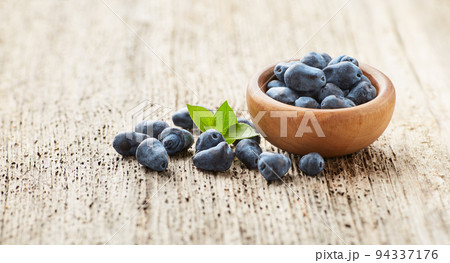 Honeysuckle berries on old wooden board. Honeyberry 94337176