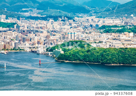 広島市街地を瀬戸内海の島の山頂から展望しています。広島港、元宇品公園が正面、大洲、東雲方面が見えます 94337608