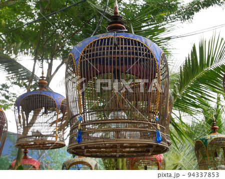 MELAKA, MALAYSIA -JUNE 7, 2022: Traditional bird cages made of bamboo are hung in an open area. Has a fabric cover to protect the bird inside from the weather. Displayed for exhibition. 94337853