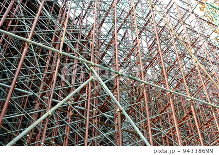 JOHOR, MALAYSIA -JUNE 6, 2022: Metal scaffolding is used as a temporary structure that supports works at the construction site. Also used as a structure for working at height outside the building. JOHOR, MALAYSIA -JUNE 6, 2022: Metal scaffolding is used as a temporary structure that supports works at the construction site. Also used as a structure for working at height outside the building. 94338699