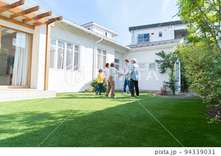庭で遊ぶ三世代家族 94339031