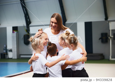 Little girls, beginner gymnastics athletes doing exercises with gymnastics equipment at sports gym, indoors. Concept of studying, achievements, skills Little girls, beginner gymnastics athletes doing exercises with gymnastics equipment at sports gym, indoors. Concept of studying, achievements, skills 94339828