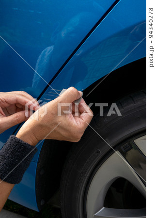 青い車のボディについた擦り傷を修理しようとしているシニア男性の手元 青い車のボディについた擦り傷を修理しようとしているシニア男性の手元 94340278