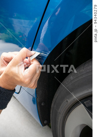 青い車のボディについた擦り傷を修理しようとしているシニア男性の手元 青い車のボディについた擦り傷を修理しようとしているシニア男性の手元 94340279