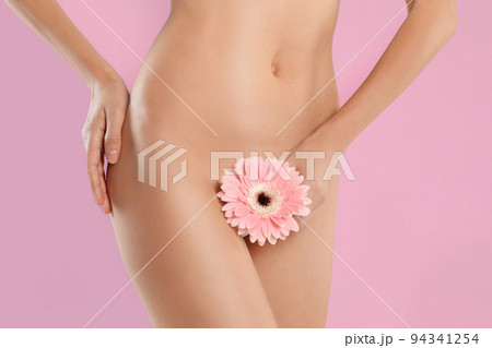 Woman with flower showing smooth skin after bikini epilation on beige background, closeup 94341254
