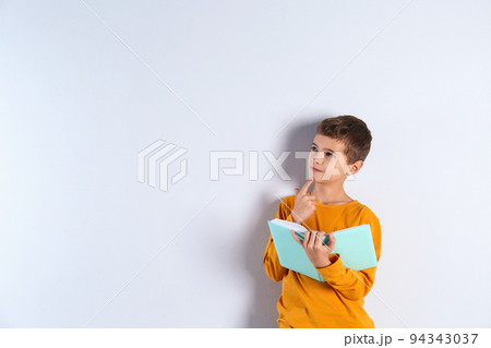 Cute little boy with book on light background, space for text 94343037