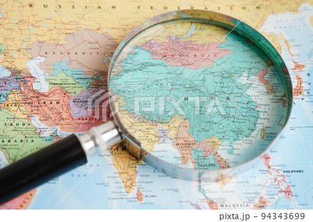 Bangkok, Thailand - May 15, 2022 Magnifying glass on world map. Bangkok, Thailand - May 15, 2022 Magnifying glass on world map. 94343699
