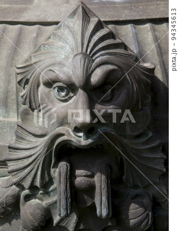 Demonic statue face made of metal on a street lamp Demonic statue face made of metal on a street lamp 94345613