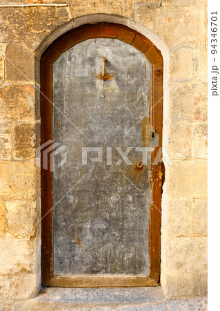 Silver colored metal door inside of stone wall 94346701