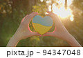Gingerbread in the shape of a heart with the flag of Ukraine in a woman's hands. 94347048