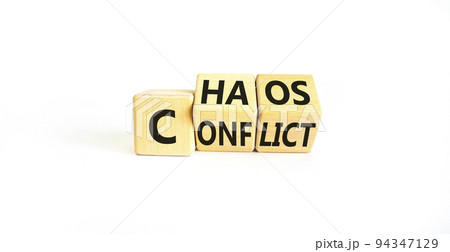 From conflict to chaos symbol. Concept words Conflict and Chaos on wooden cubes. Beautiful white table white background. Businessman hand. Business Conflict and Chaos concept. Copy space. 94347129