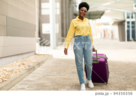 Joyful Black Female Posing With Suitcase Walking At Airport Outdoors 94350356