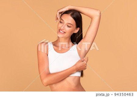 Reducing body odor. Happy fit lady standing with one hand up, demonstrating her smooth depilated armpit Reducing body odor. Happy fit lady standing with one hand up, demonstrating her smooth depilated armpit 94350463