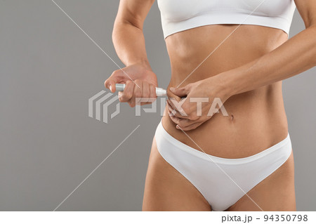 Insulin Dependence. Slim young woman in underwear making insulin injection to waist side Insulin Dependence. Slim young woman in underwear making insulin injection to waist side 94350798