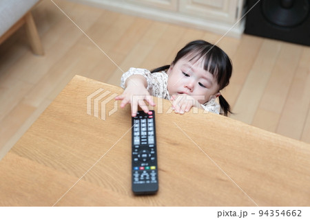 テレビのリモコンをいたずらする1歳の女の子 94354662