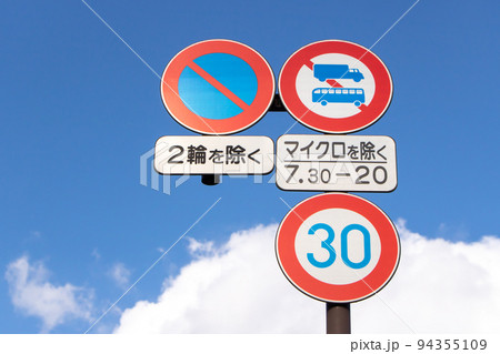 たくさんの道路標識と青空。本標識(規制標識)3枚と補助標識2枚。の写真